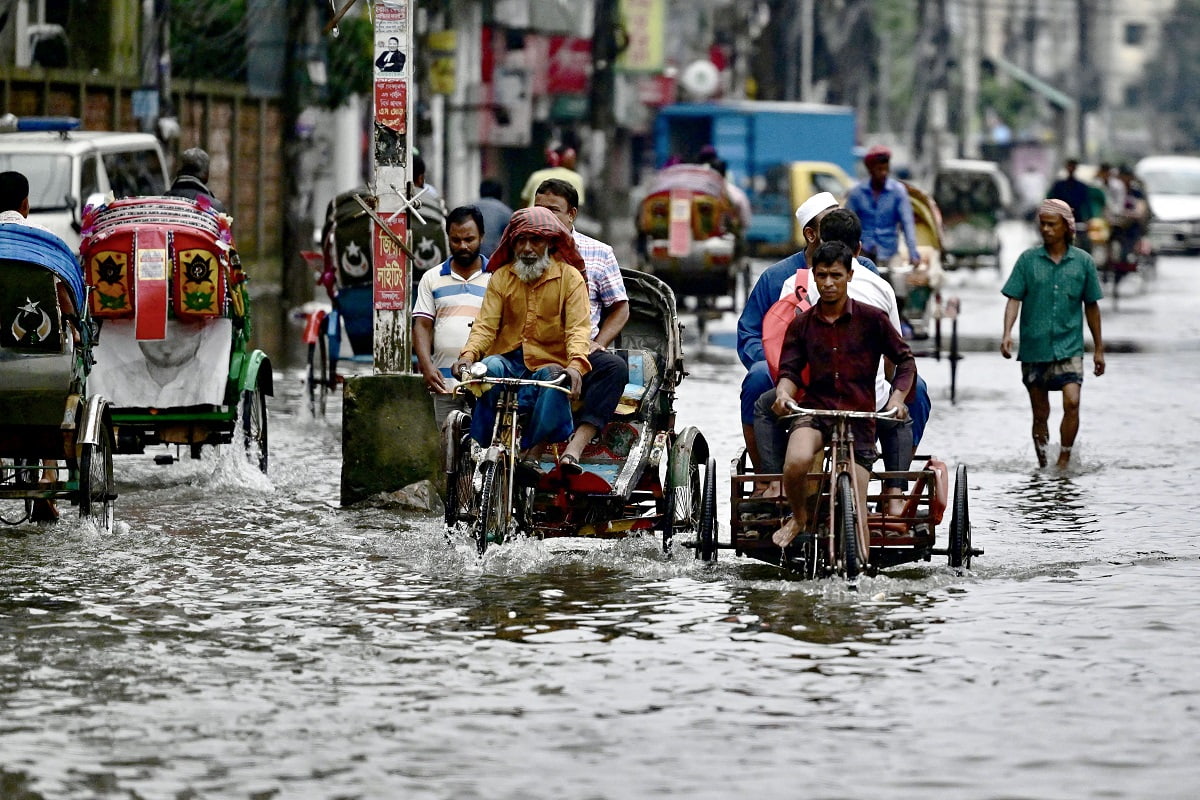  Commuters wade through a flooded street in Sylhet on June 20, 2024. Torrential rains in Bangladesh have triggered landslides burying alive at least nine people and forcing thousands to flee to higher ground, police and government officials in the low-lying nation said on June 19. In Sylhet, lashing rain and rivers swollen by flooding upstream in India also swamped heavily populated areas. (Photo by Mamun Hossain / AFP) (Photo by MAMUN HOSSAIN/AFP via Getty Images)