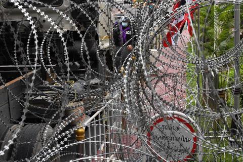 Police stand behind coils of barbed wire ahead of expected pro-democracy protests in Bangkok on 18 November (Mladen Antonov/AFP via Getty Images)